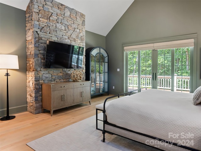 bedroom with high vaulted ceiling, a fireplace, french doors, light hardwood / wood-style floors, and access to outside