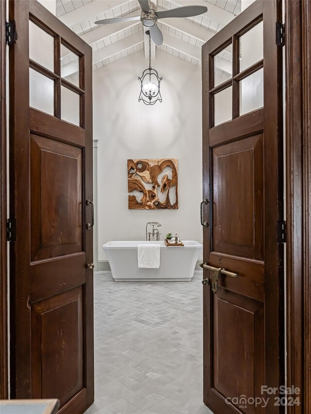 interior space with ceiling fan, vaulted ceiling, and light tile patterned floors