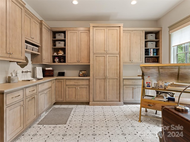 kitchen with light brown cabinetry and built in desk