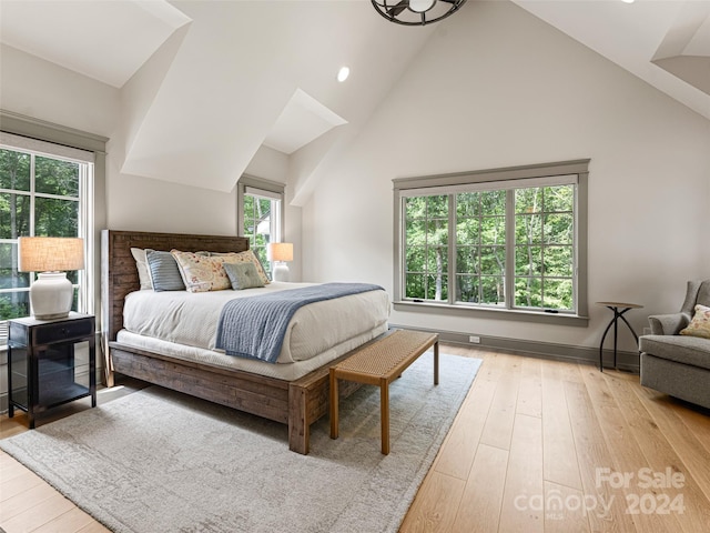 bedroom with light hardwood / wood-style floors, high vaulted ceiling, and multiple windows