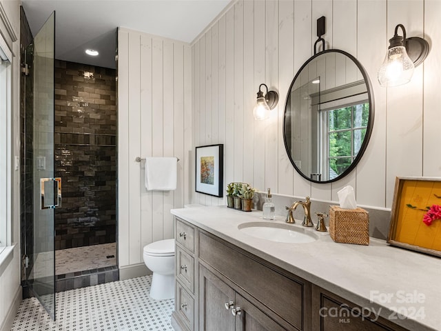 bathroom with toilet, wooden walls, vanity, tile patterned floors, and walk in shower