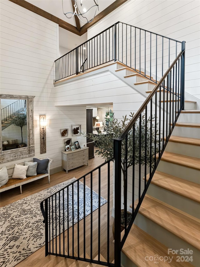 stairs with hardwood / wood-style floors and a high ceiling