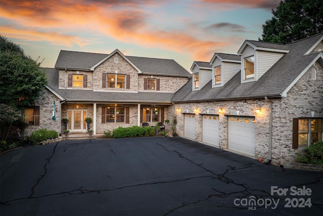 view of front of property with an attached garage, brick siding, covered porch, and driveway