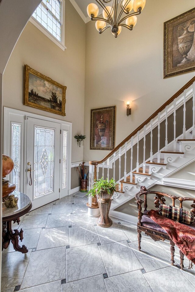 foyer entrance with tile patterned flooring, a towering ceiling, and an inviting chandelier