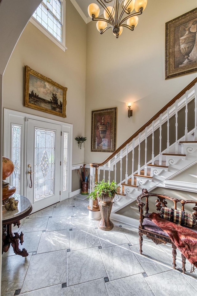 entryway with stairs, a high ceiling, baseboards, and a chandelier