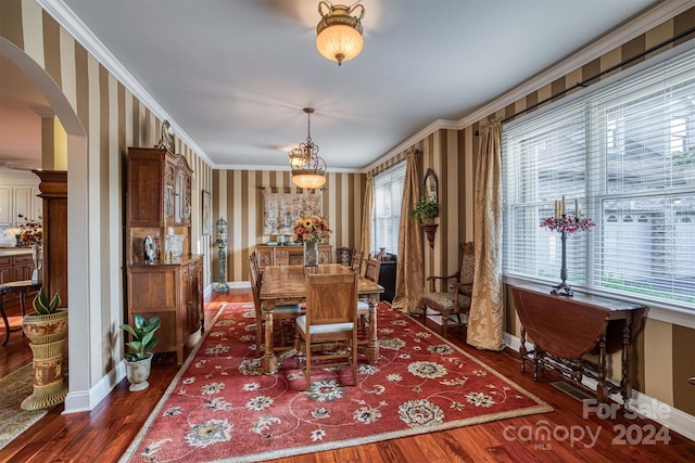 dining room with arched walkways, wood finished floors, and ornamental molding