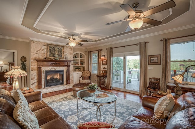 living room with a high end fireplace, wood-type flooring, built in features, and ceiling fan