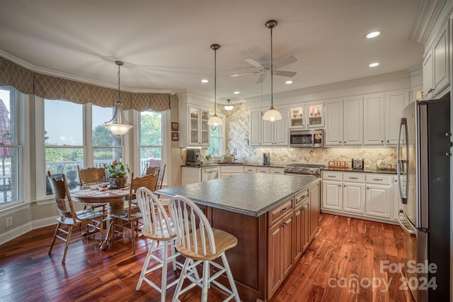 kitchen with stainless steel appliances, glass insert cabinets, dark countertops, and ornamental molding