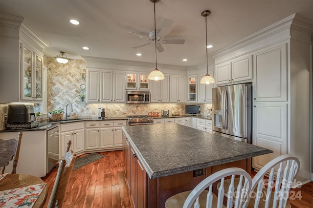 kitchen featuring wood finished floors, a sink, appliances with stainless steel finishes, dark countertops, and backsplash