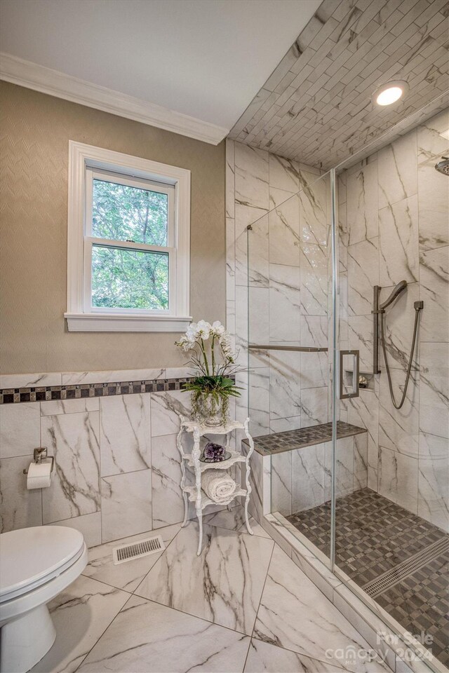 bathroom featuring crown molding, toilet, marble finish floor, and a marble finish shower