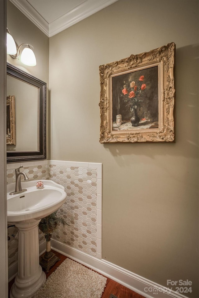 bathroom featuring a sink, wood finished floors, baseboards, and ornamental molding