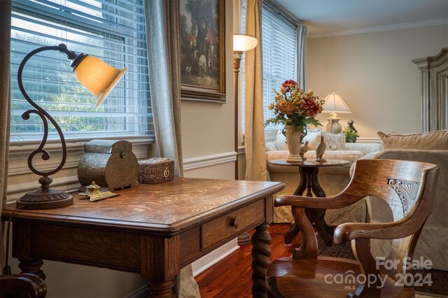 living area with a wealth of natural light, dark hardwood / wood-style floors, and ornamental molding