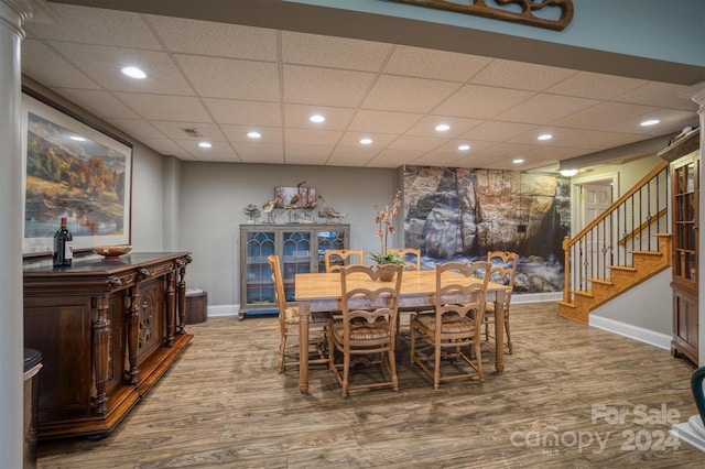 dining area with a drop ceiling, wood finished floors, recessed lighting, baseboards, and stairs