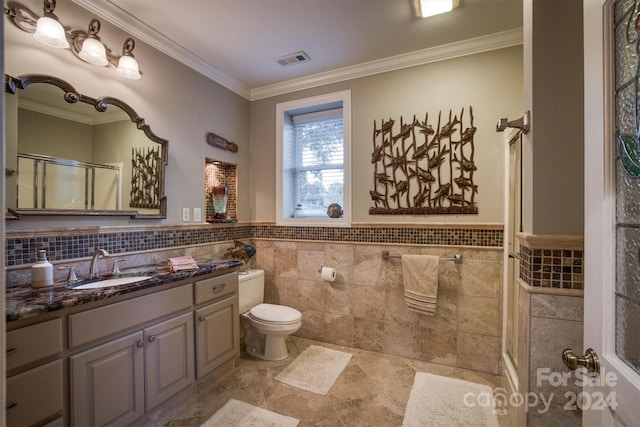 bathroom featuring vanity, visible vents, crown molding, toilet, and a shower with door