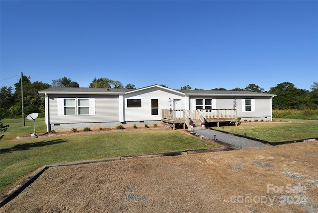 manufactured / mobile home featuring a wooden deck and a front lawn