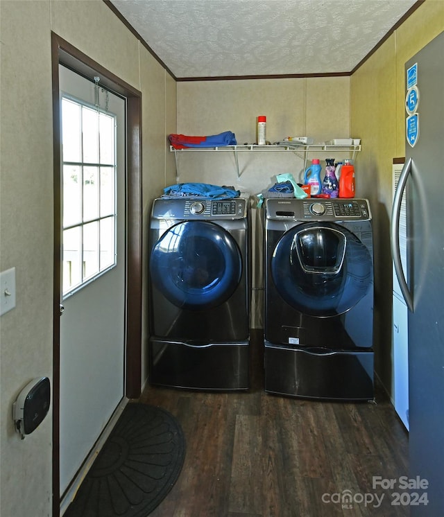 clothes washing area with ornamental molding, a textured ceiling, washer and clothes dryer, and dark hardwood / wood-style floors