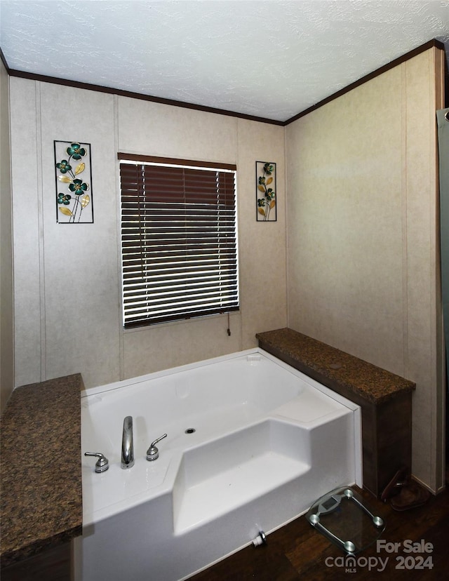 bathroom featuring a tub, a textured ceiling, wood-type flooring, and ornamental molding