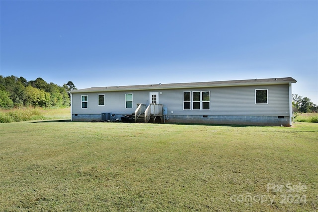 back of house with cooling unit and a lawn