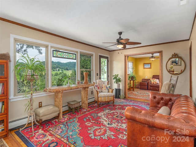 living room with ceiling fan, ornamental molding, a baseboard radiator, and wood-type flooring