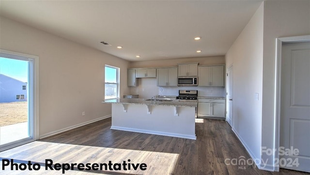 kitchen featuring a center island with sink, range, sink, light stone counters, and dark hardwood / wood-style floors