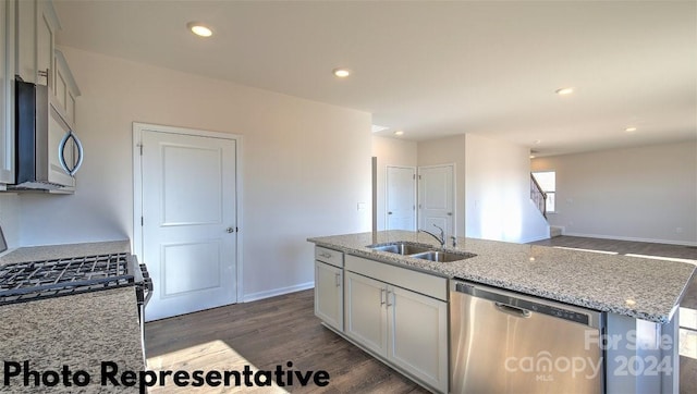 kitchen featuring a kitchen island with sink, dark hardwood / wood-style flooring, light stone countertops, sink, and appliances with stainless steel finishes