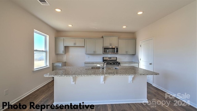 kitchen featuring a center island with sink, stainless steel appliances, and light stone countertops