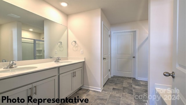 bathroom featuring a shower with shower door and vanity