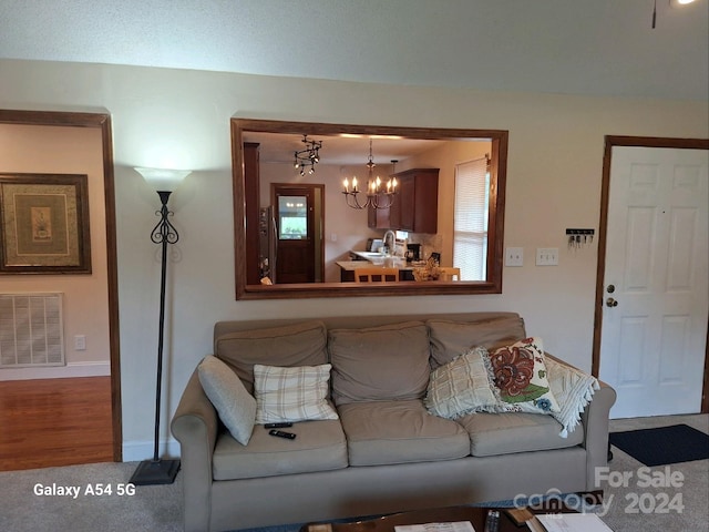 living room featuring an inviting chandelier, sink, and carpet