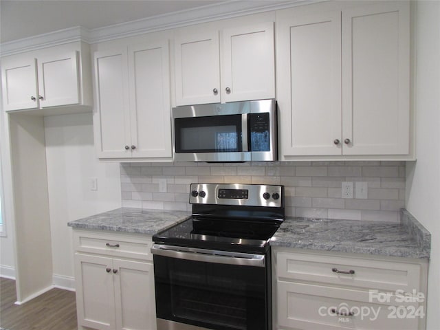 kitchen with light stone countertops, white cabinetry, backsplash, and appliances with stainless steel finishes