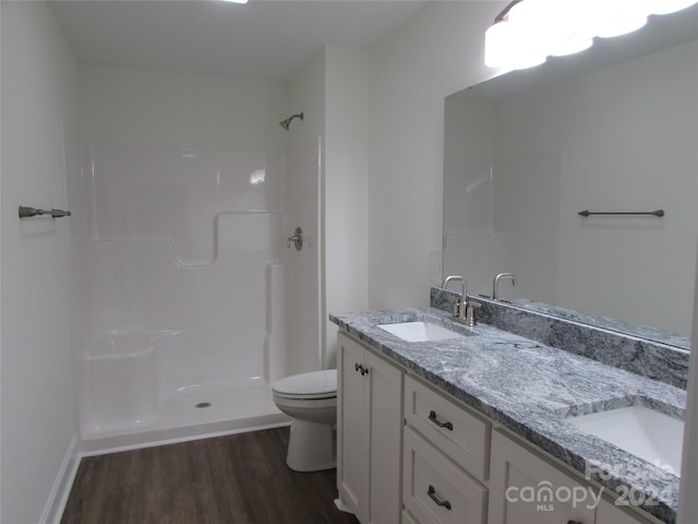 bathroom featuring hardwood / wood-style floors, vanity, toilet, and a shower