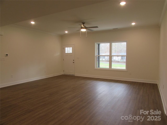 empty room with dark hardwood / wood-style flooring, ceiling fan, and crown molding