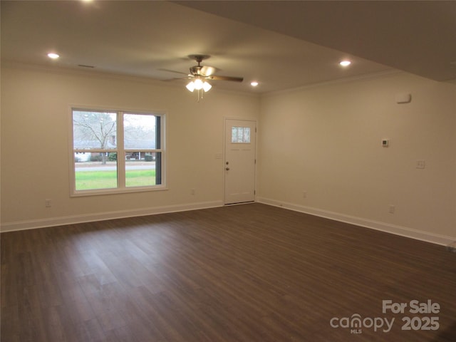 empty room with ceiling fan, crown molding, and dark wood-type flooring