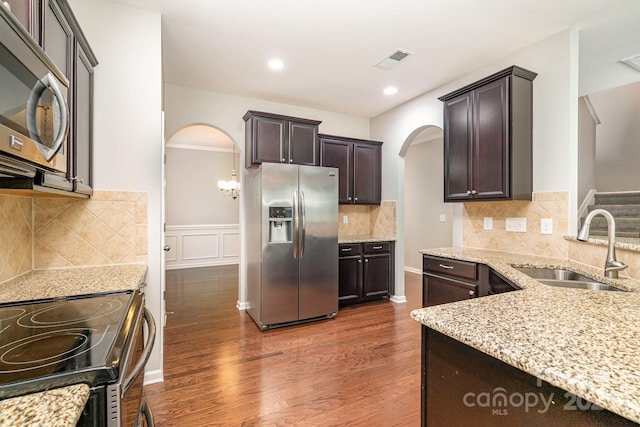 kitchen with sink, dark brown cabinets, decorative backsplash, dark hardwood / wood-style floors, and stainless steel appliances