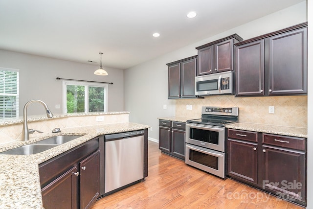 kitchen with appliances with stainless steel finishes, a healthy amount of sunlight, light wood-type flooring, and sink