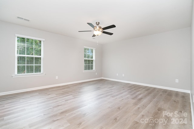 empty room with ceiling fan, light hardwood / wood-style floors, and a healthy amount of sunlight