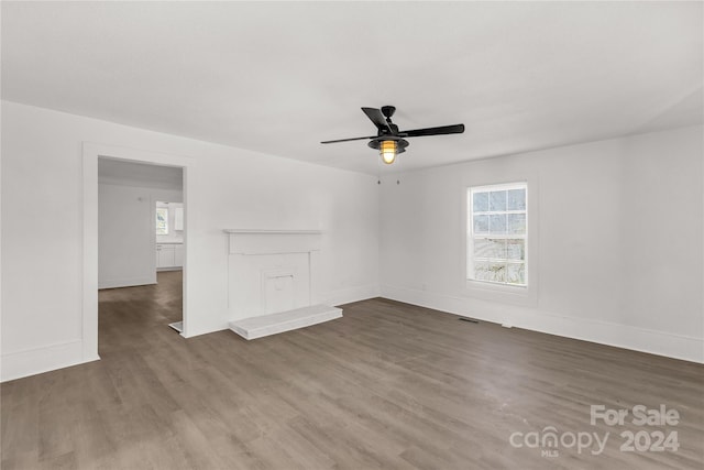 unfurnished living room with ceiling fan, a healthy amount of sunlight, and dark hardwood / wood-style flooring