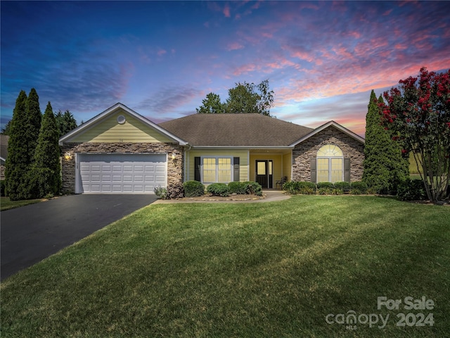 single story home with a garage, a shingled roof, stone siding, a yard, and driveway