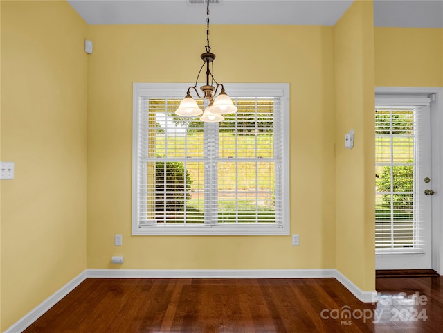 unfurnished dining area featuring a notable chandelier and wood-type flooring