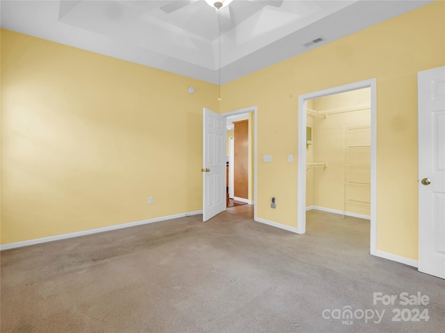 unfurnished room featuring a towering ceiling, ceiling fan, a raised ceiling, and light carpet