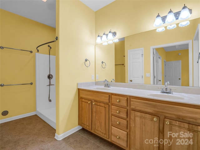 bathroom featuring tile patterned flooring, double vanity, and walk in shower