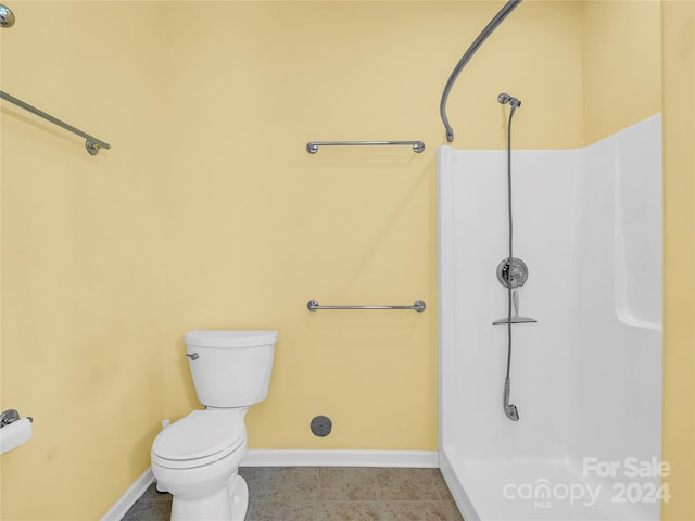 full bathroom featuring a shower, toilet, and baseboards