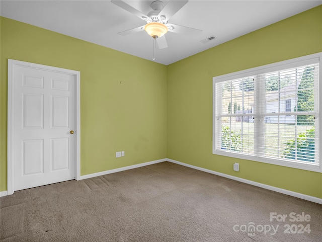 unfurnished room with carpet, visible vents, and baseboards