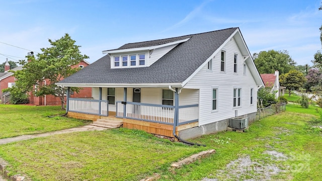 view of front facade with covered porch, central AC, and a front yard