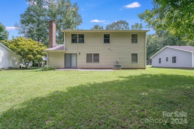 rear view of house with cooling unit and a lawn