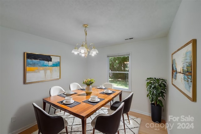 dining area featuring visible vents, a chandelier, light wood-style flooring, and baseboards