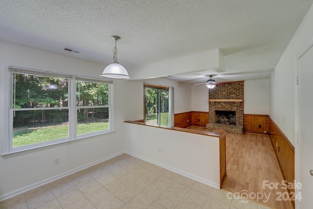 kitchen featuring a peninsula, pendant lighting, open floor plan, and wainscoting