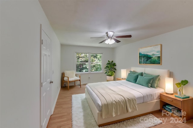 bedroom with ceiling fan, light wood-style flooring, and baseboards