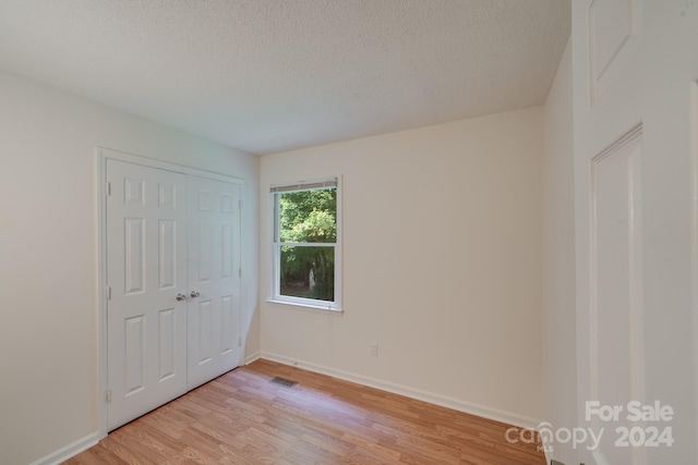 unfurnished bedroom featuring light wood-type flooring, baseboards, visible vents, and a textured ceiling