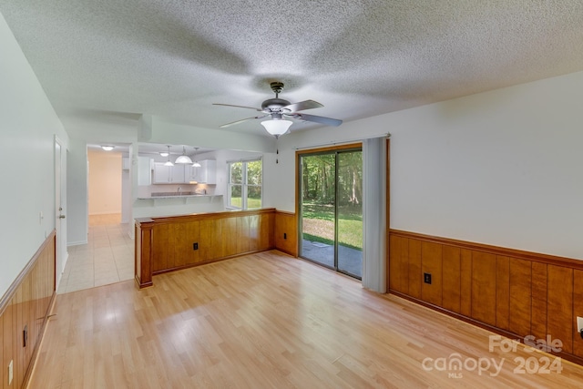 kitchen with brown cabinetry, light countertops, wainscoting, and light wood finished floors