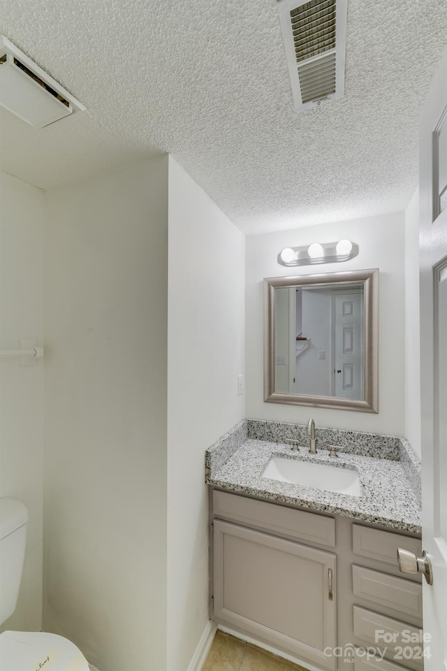 half bathroom with toilet, visible vents, a textured ceiling, and vanity